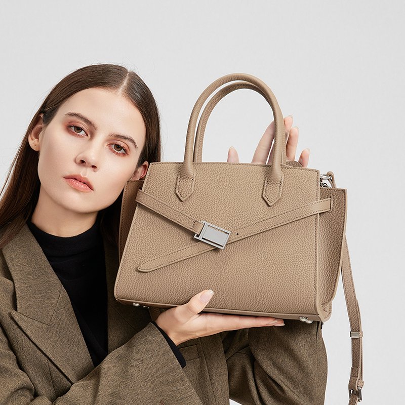 a woman wearing the Aura model of a luxury handbag from the Donna Puo brand in beige color