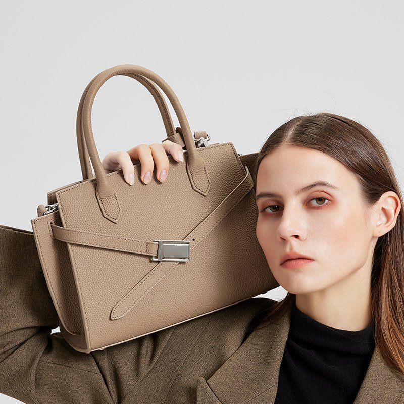 a woman wearing the Aura model of a luxury handbag from the Donna Puo brand in beige color