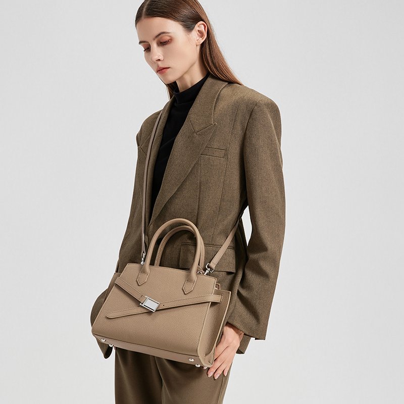 a woman wearing the Aura model of a luxury handbag from the Donna Puo brand in beige color